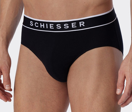 Muž má na sobě černé slipy Rio s biobavlnou SCHIESSER.