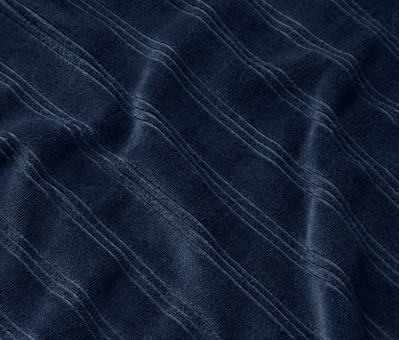 Detailní záběr na tmavě modrou látku s reliéfními pruhy.