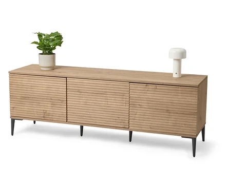 Světlý dřevěný sideboard s rostlinou v květináči a lampou.