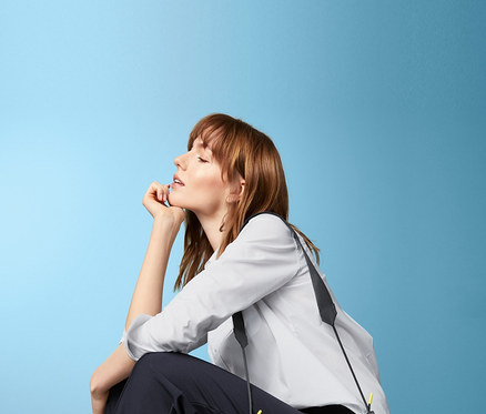 Žena sedí s žlutou taškou přes rameno.