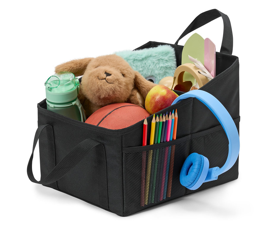 Černý organizér naplněný hračkami, pastelkami, sluchátky a jablkem.