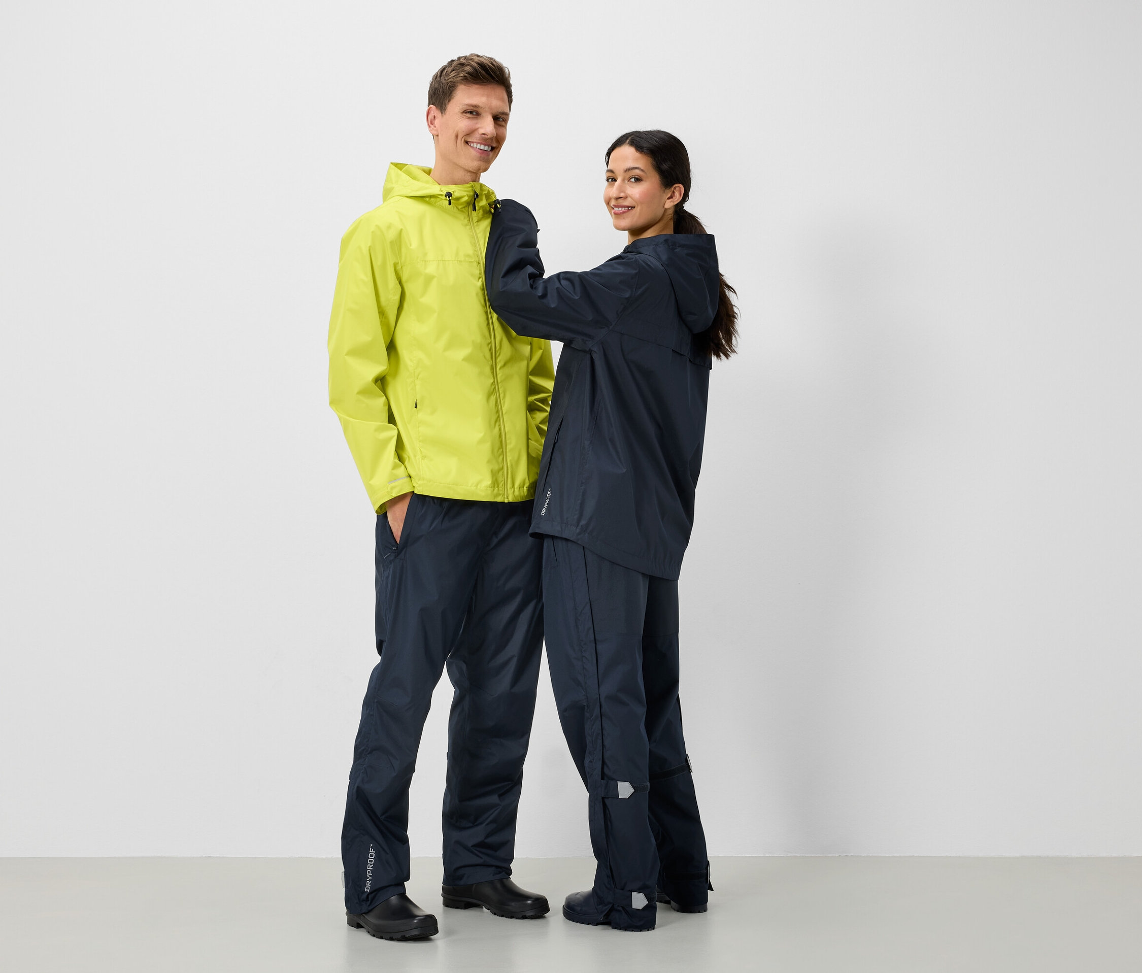 Dva lidé v pláštěnkách a kalhotách do deště, muž v žluté a žena v tmavě modré.