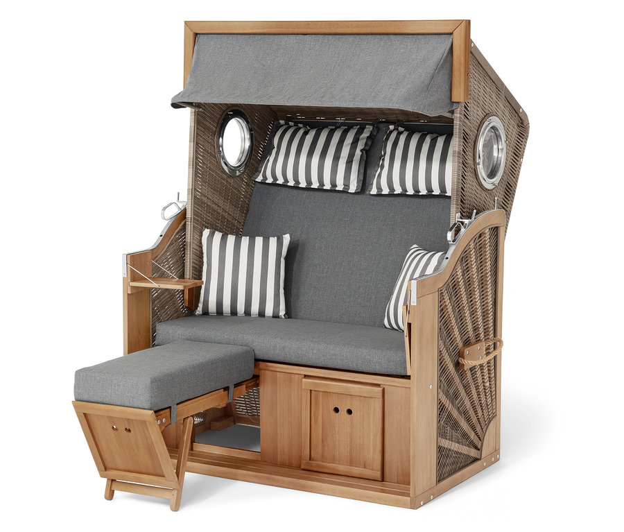 Plážový koš z proutí a dřeva se šedými polštáři a pruhovanými polštáři.