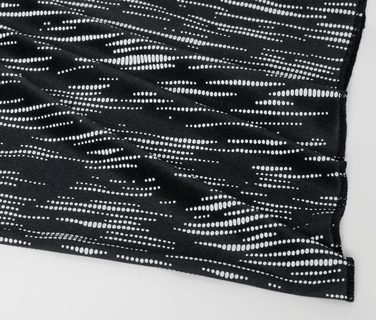 Detail černého látkového pouzdra s bílým tečkovaným vzorem.