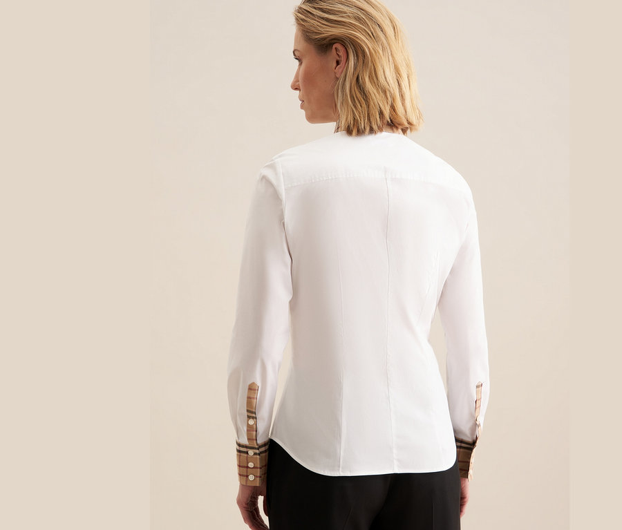 Zezadu je vidět žena v bílé popelínové halence Seidensticker s kostkovanými detaily na manžetách.