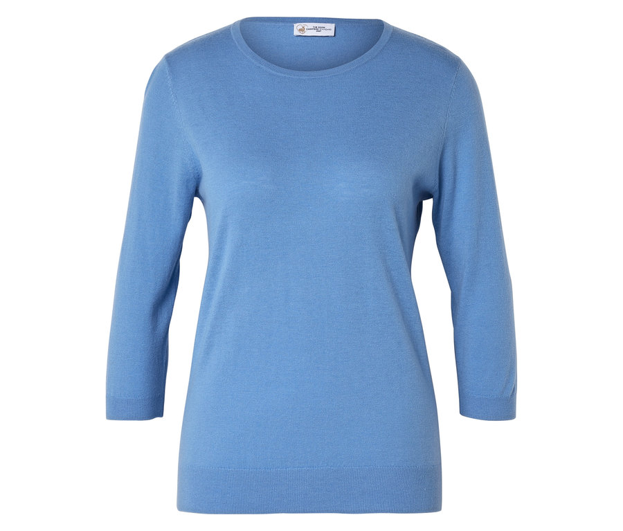 Světle modrý svetr s tříčtvrtečními rukávy leží na bílém povrchu.