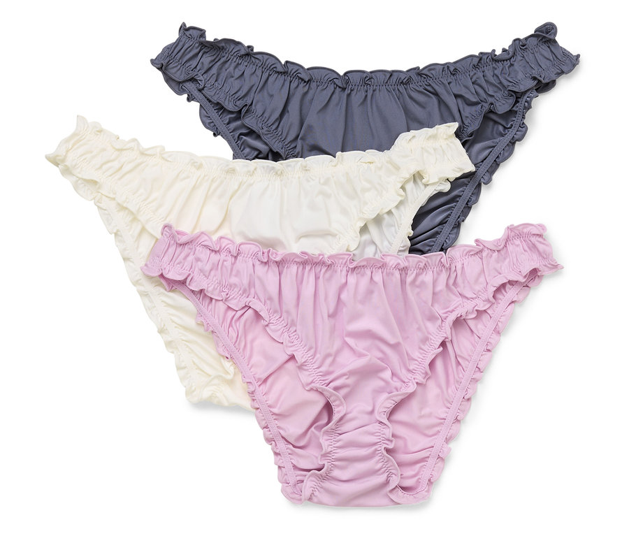 Tři dámské kalhotky v šedé, krémové a fialové barvě leží na sobě.