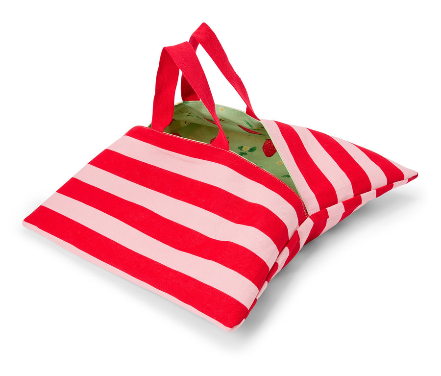 Červeno-bílá pruhovaná taška s červenými uchy a zelenou podšívkou s jahodovým vzorem leží na bílém povrchu.