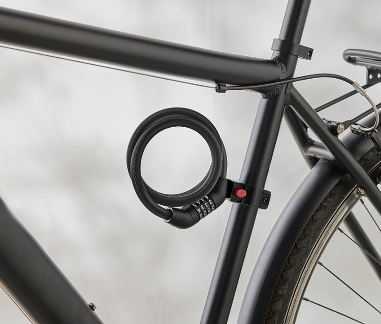 Detail černého rámu kola se spirálovým číselným zámkem připevněným k rámu.