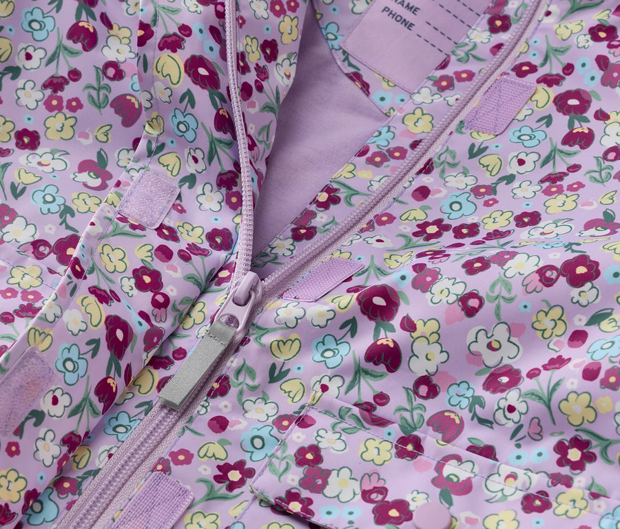 Detail fialové dětské bundy s květinovým vzorem, rozepnuté na zip.