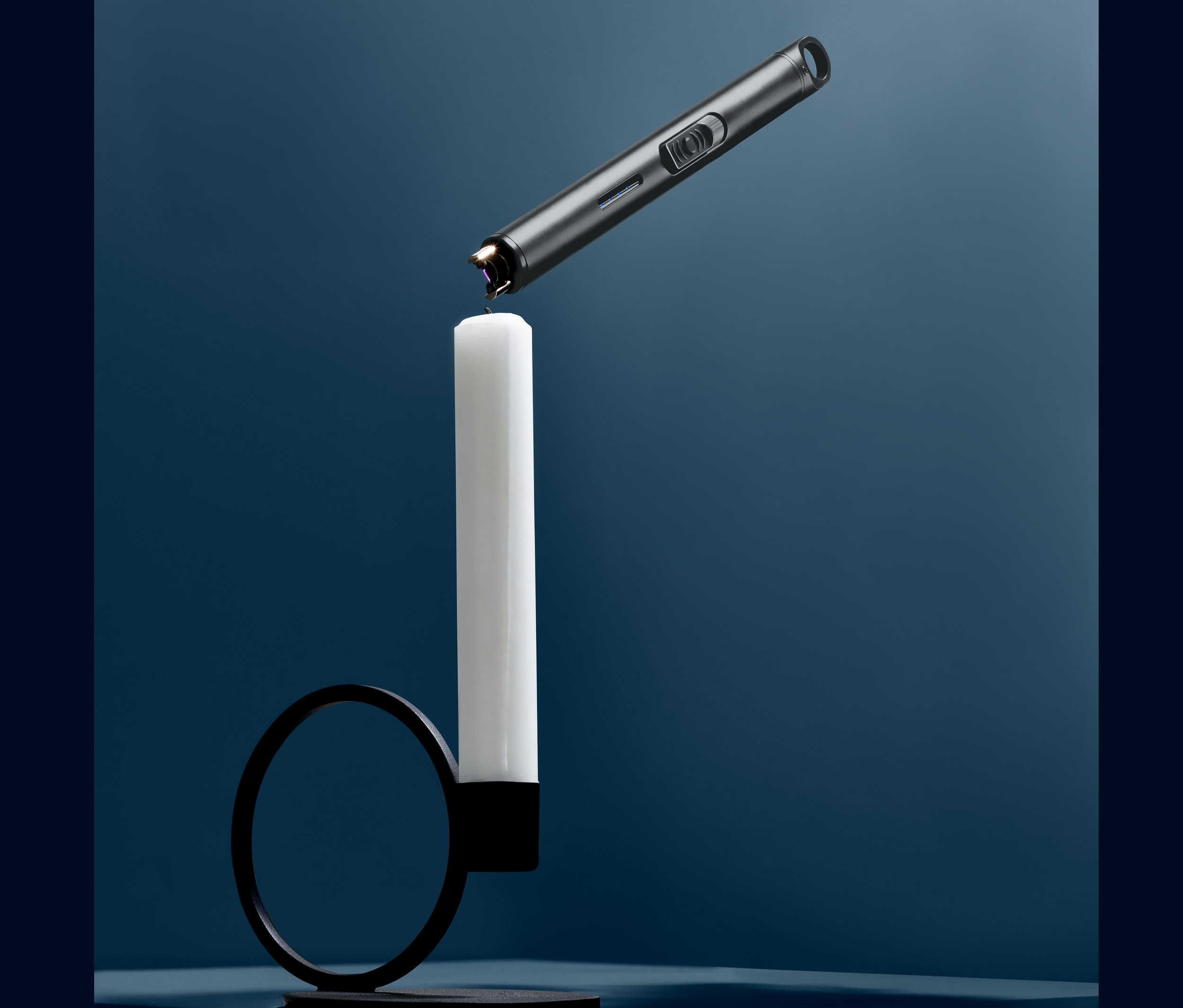 Šedý elektrický zapalovač zapaluje bílou svíčku v černém svícnu.