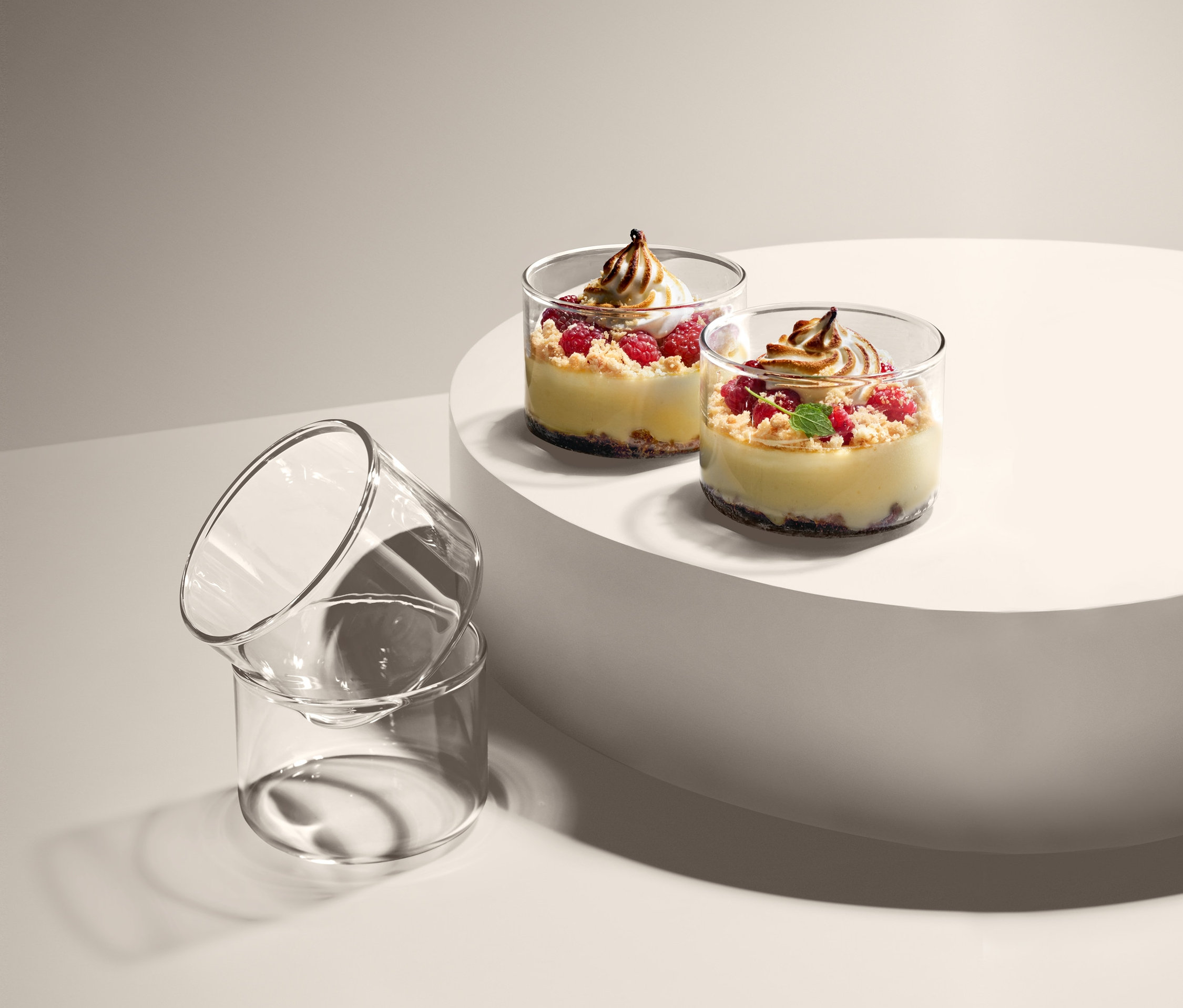 Dva dezerty ve skleněných miskách na bílém podstavci, vedle nich leží další dvě prázdné skleněné misky na servírování a zapékání, 4 ks.