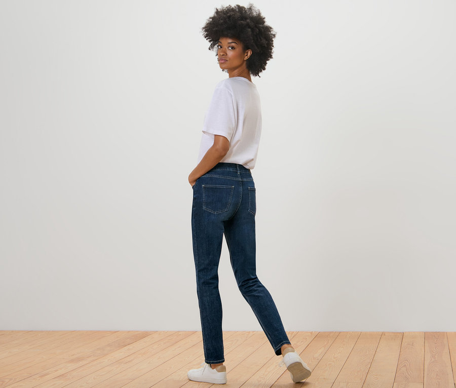 Černoška se dívá přes rameno a pózuje ve tmavě modrých džínách slim-fit »Emma«.