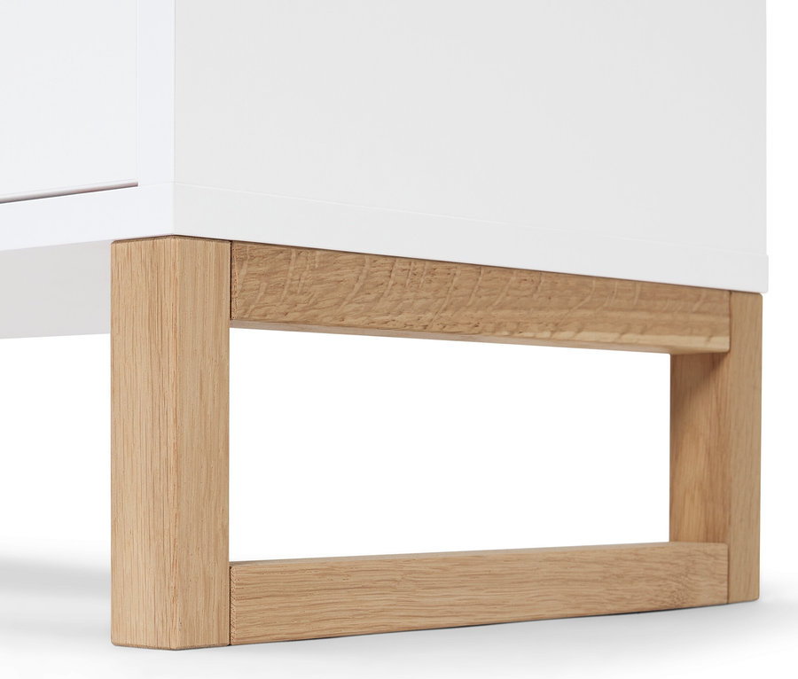 Detail odkládací skříňky se 2 zásuvkami a 2 dvířky, bílá skříňka s dřevěnýma nohama.