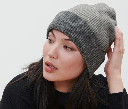 Žena sedí na židli a má na sobě šedou pletenou čepici.