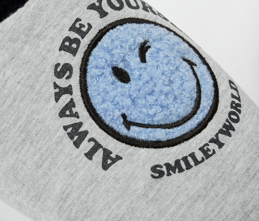 Detail šedé pantofle SMILEYWORLD® s modrým usměvavým obličejem.