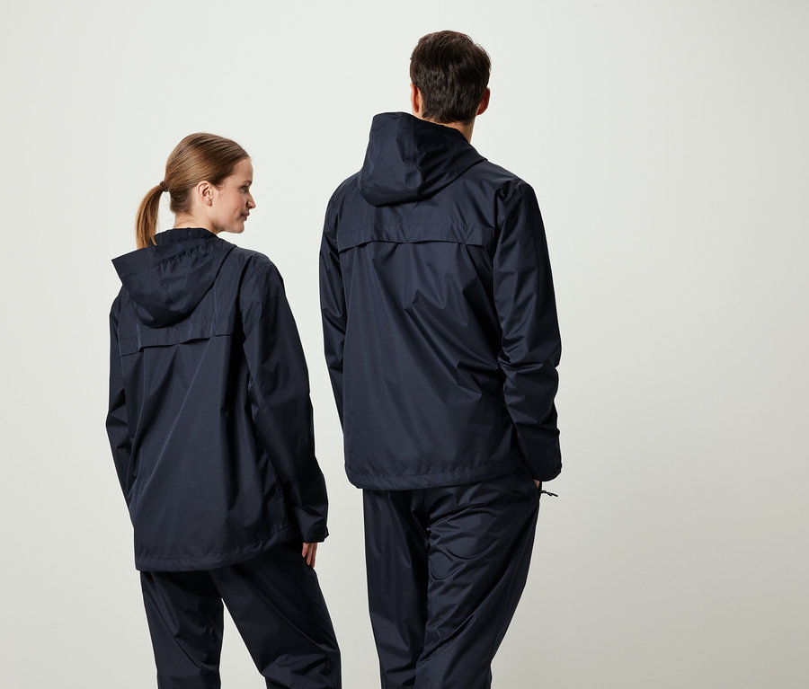 Dva lidé zády ke kameře v odpovídajících tmavě modrých bundách s kapucí a kalhotách.
