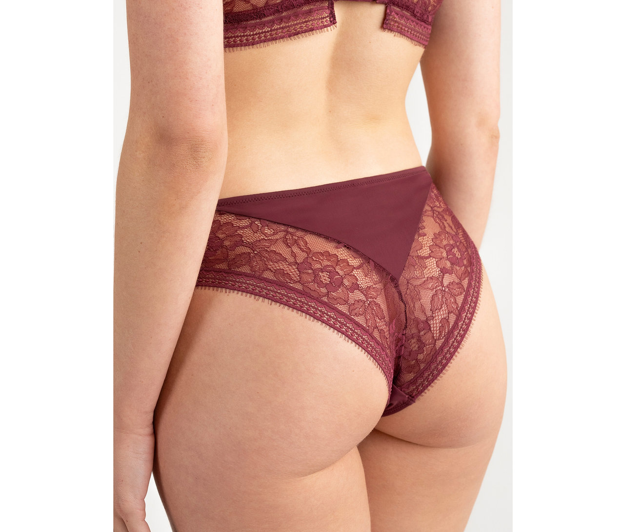 Pohled zezadu na osobu v vínových kalhotkách s vysokým pasem Passionata high waist »Jeanne« s krajkovými detaily.