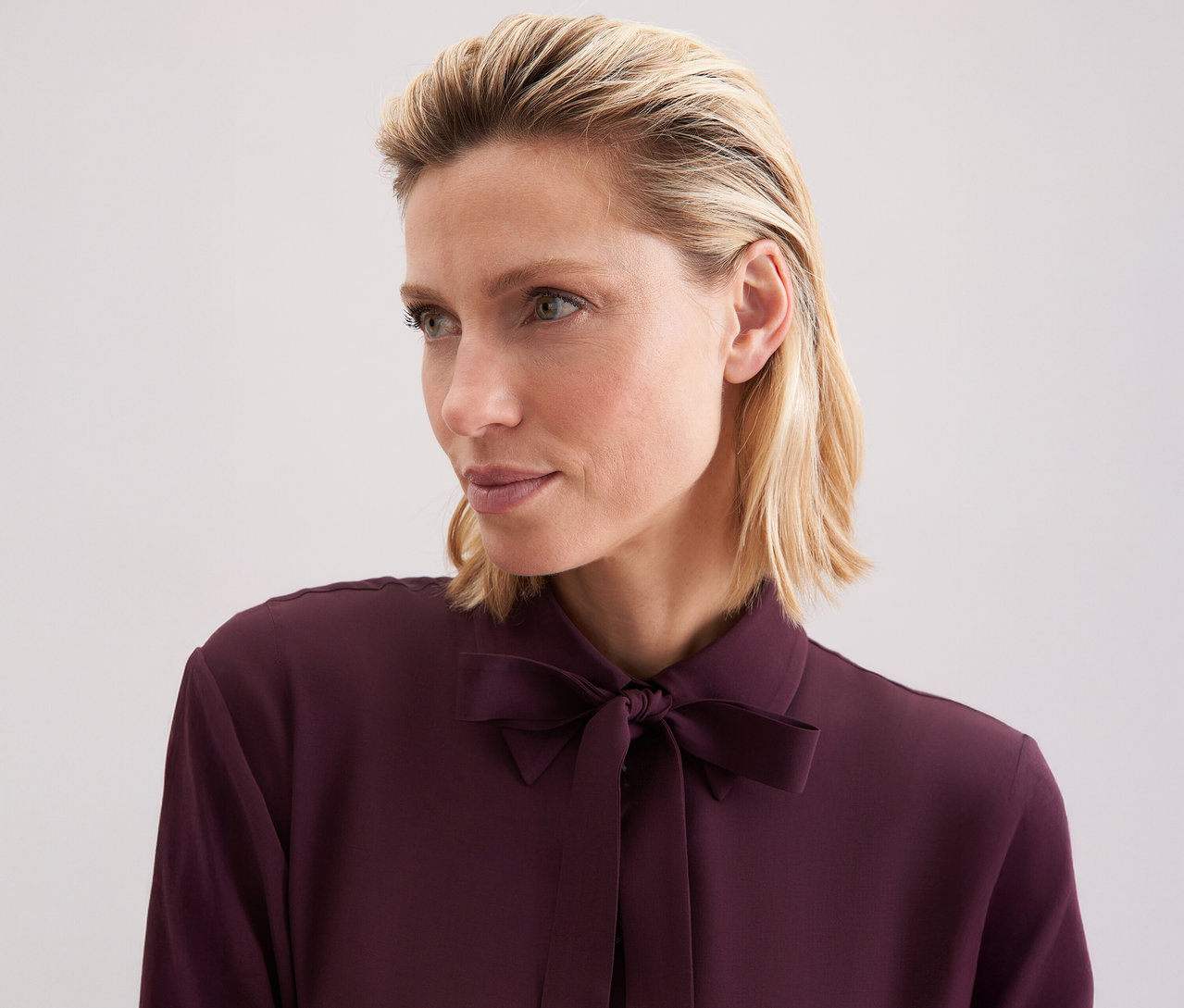 Žena má na sobě viskózovou halenku s vázačkou Seidensticker.