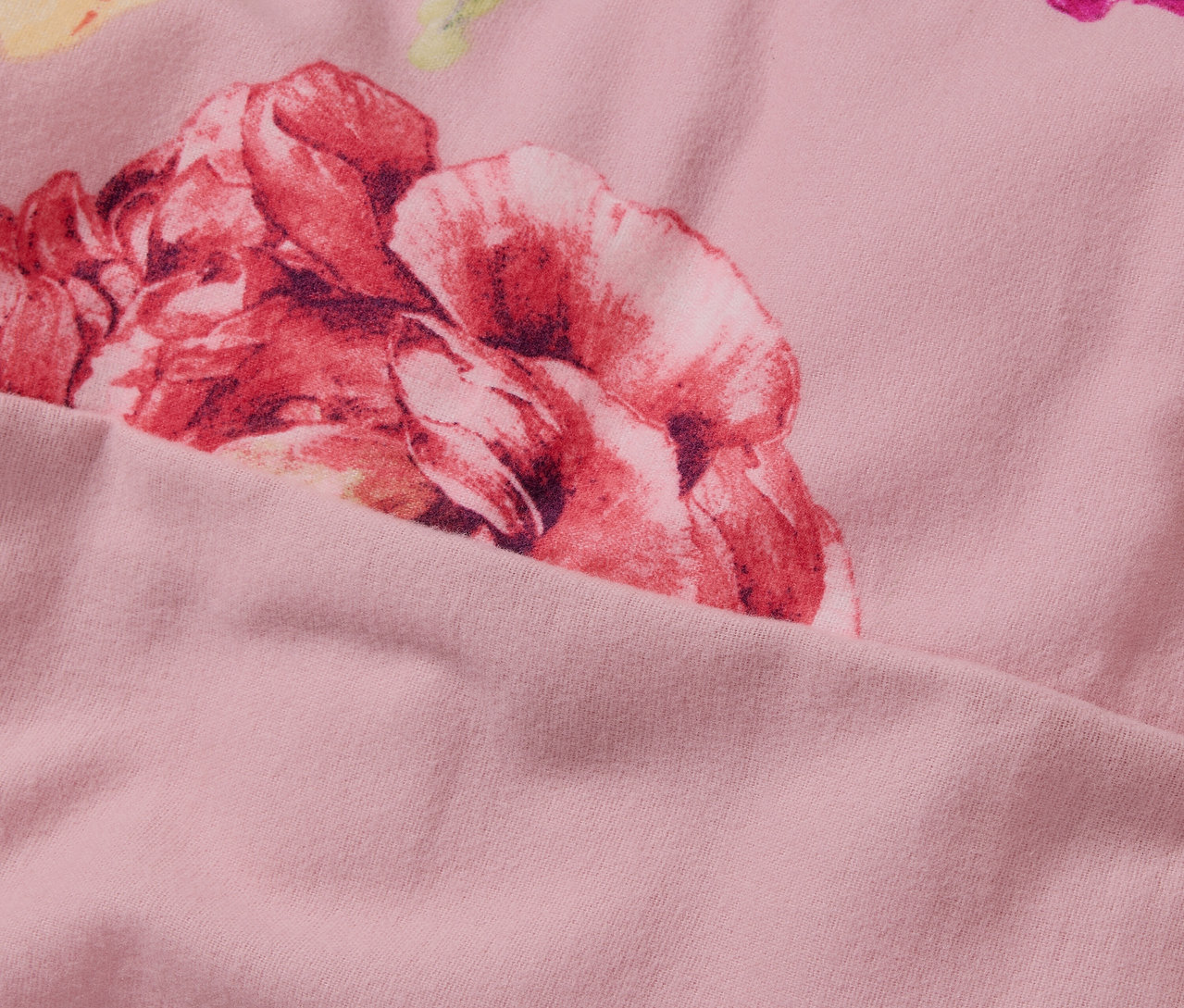 Detailní záběr na růžové flanelové povlečení standardní velikosti s květinovým vzorem.