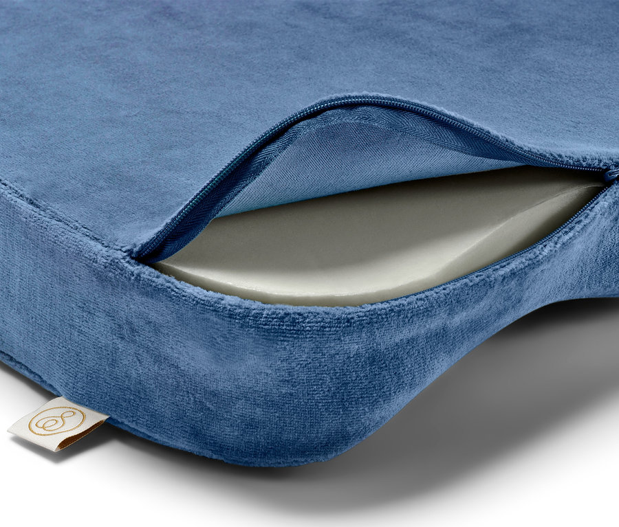 Detail modrého polštáře se zipem, odkrývajícím bílou pěnovou výplň.