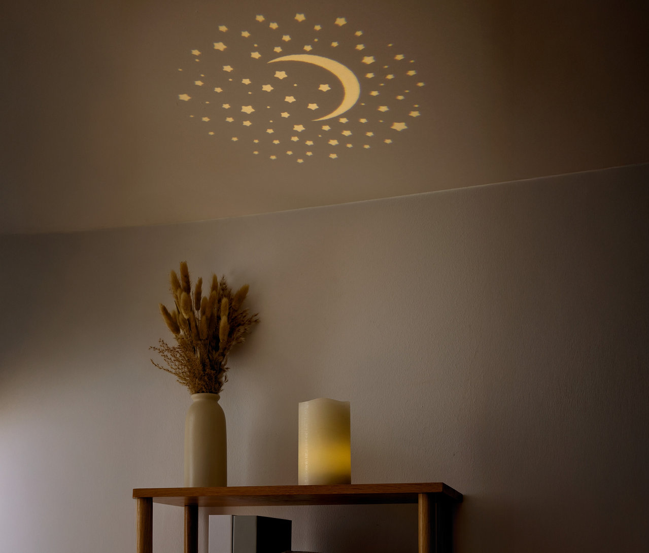 Na stropě jsou vidět hvězdy a půlměsíc. Na polici stojí váza se sušenými květinami a svíčka.
