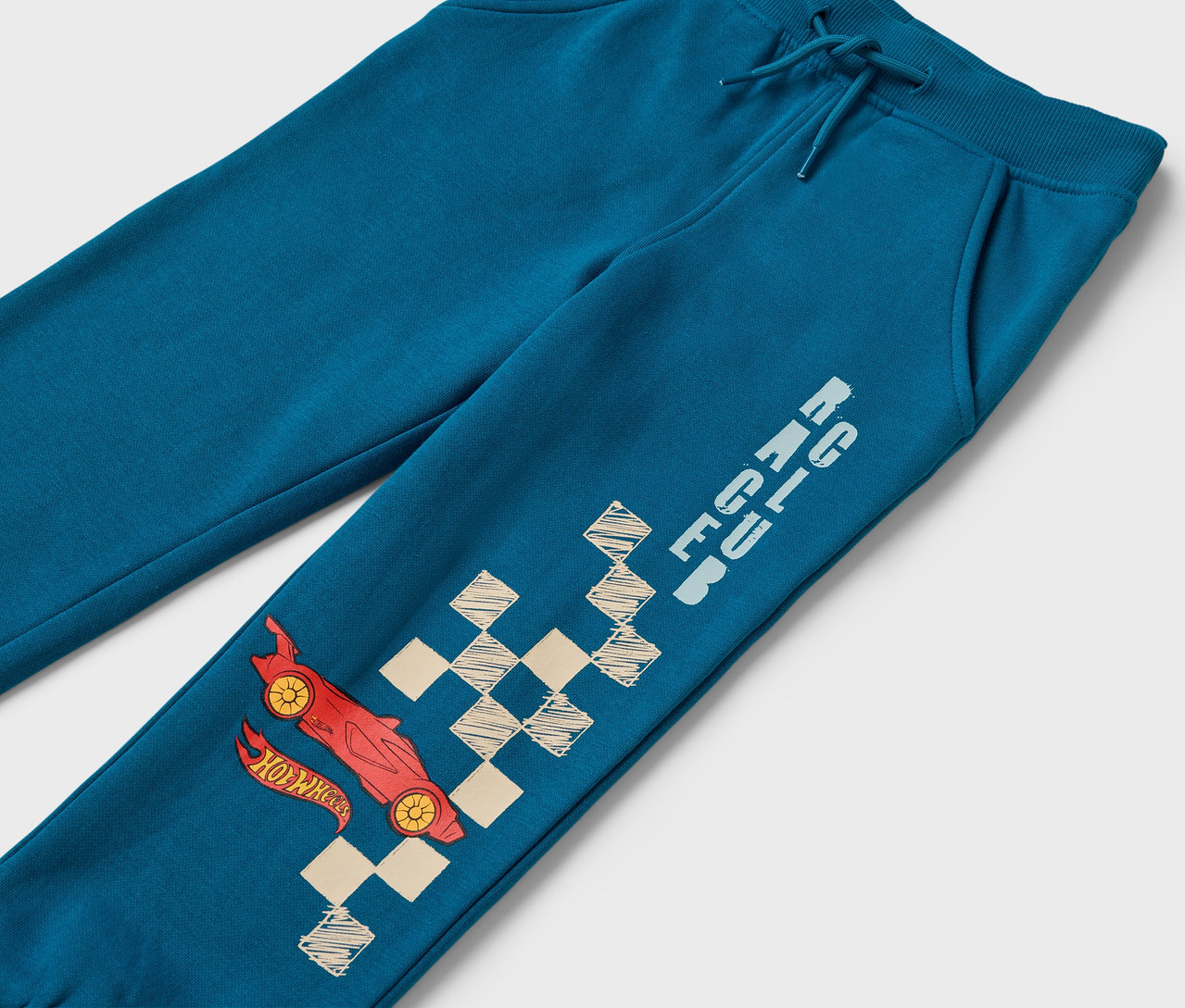 Modré tepláky s obrázkem červeného auta a šachovnicového vzoru.