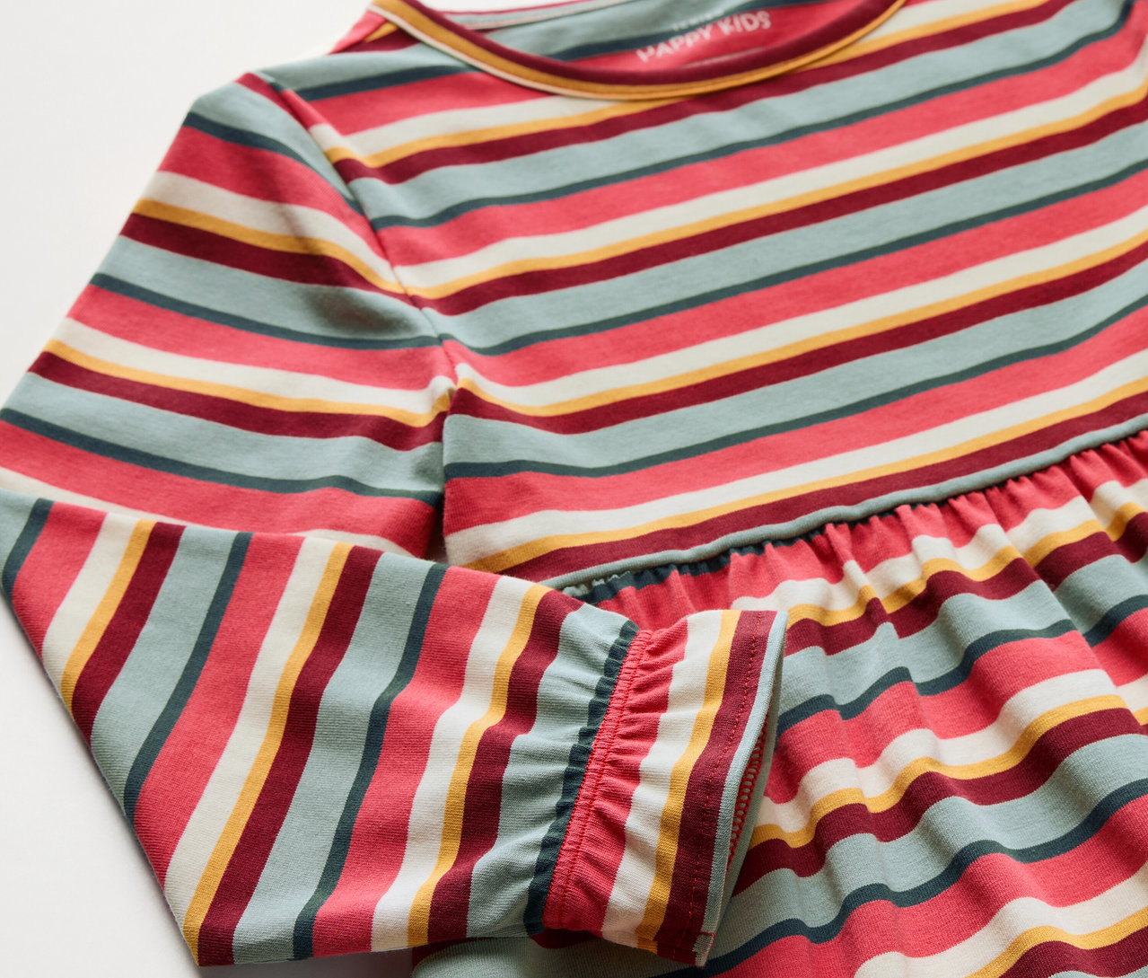 Detail dětských jersey šatů s barevnými pruhy.