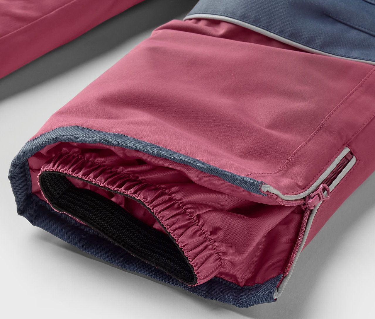 Detail nohavice z 2dílné dětské zimní kombinézy růžovo-modré barvy.