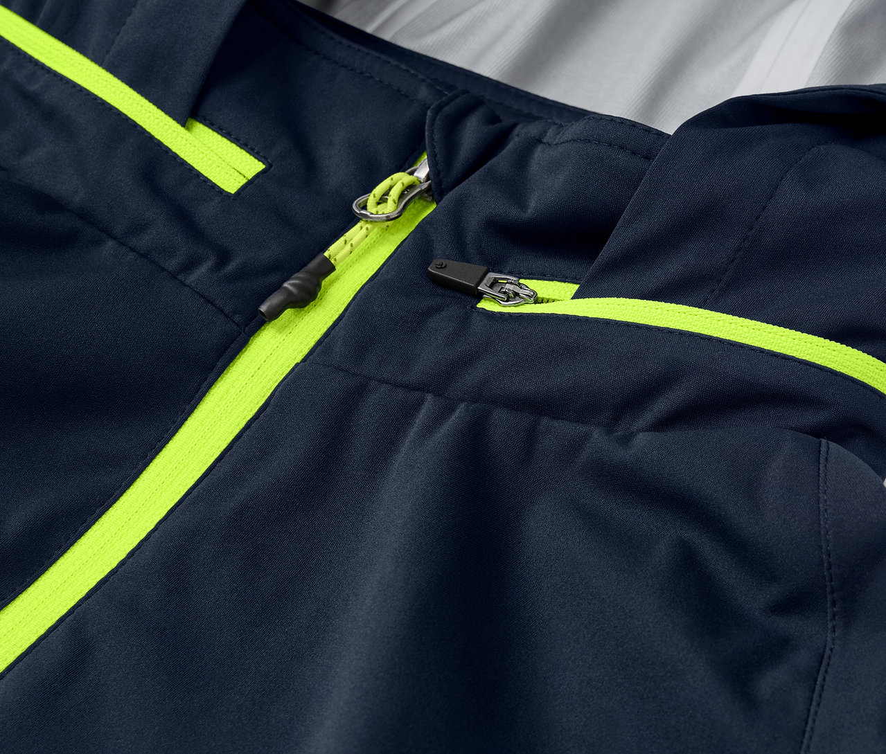 Detailní záběr na cyklistickou bundu do deště s neonově žlutými detaily zipu a lemováním.