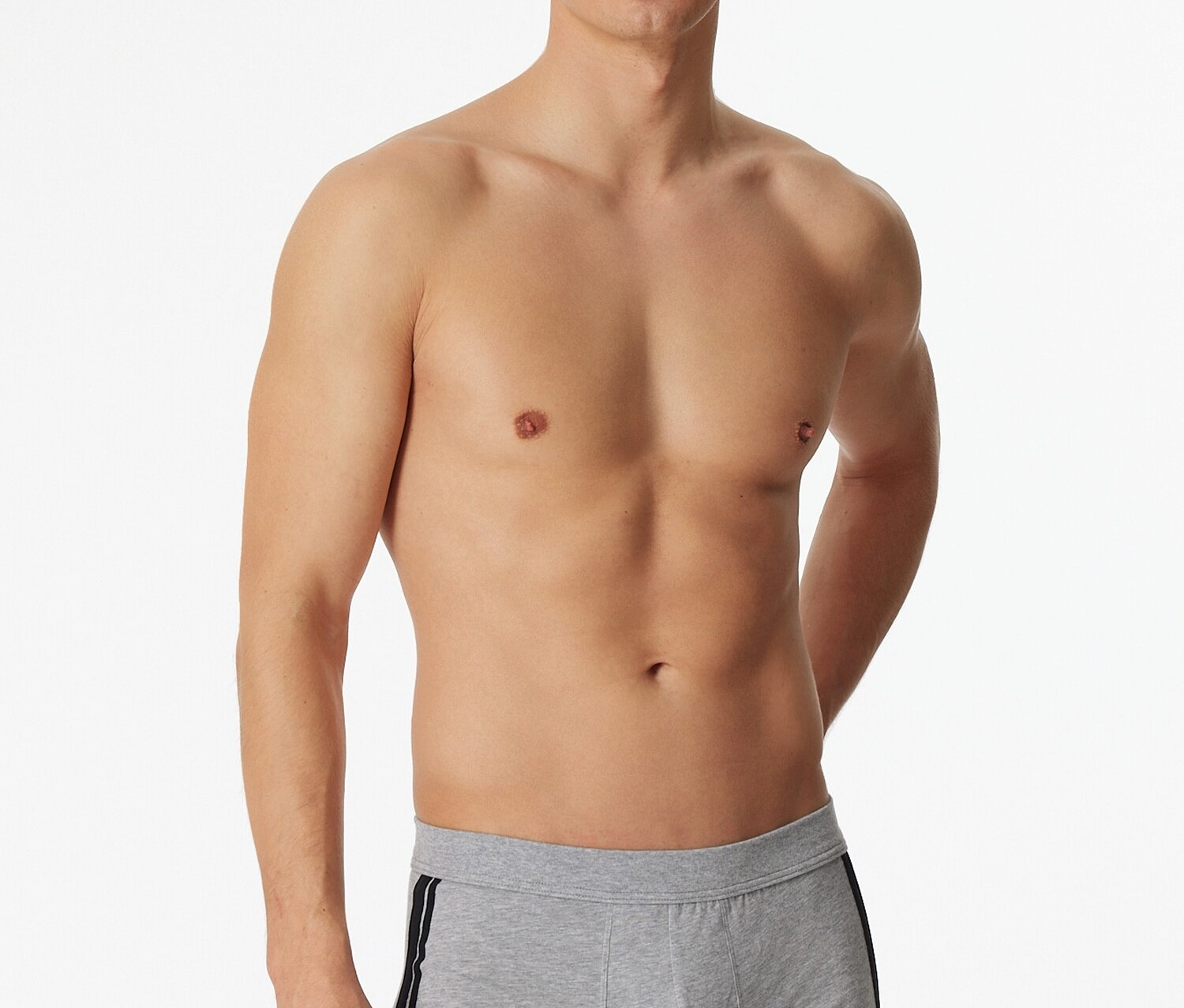 Muž pózuje bez trička ve světle šedých boxerkách SCHIESSER s melírem a černým pruhem na boku.