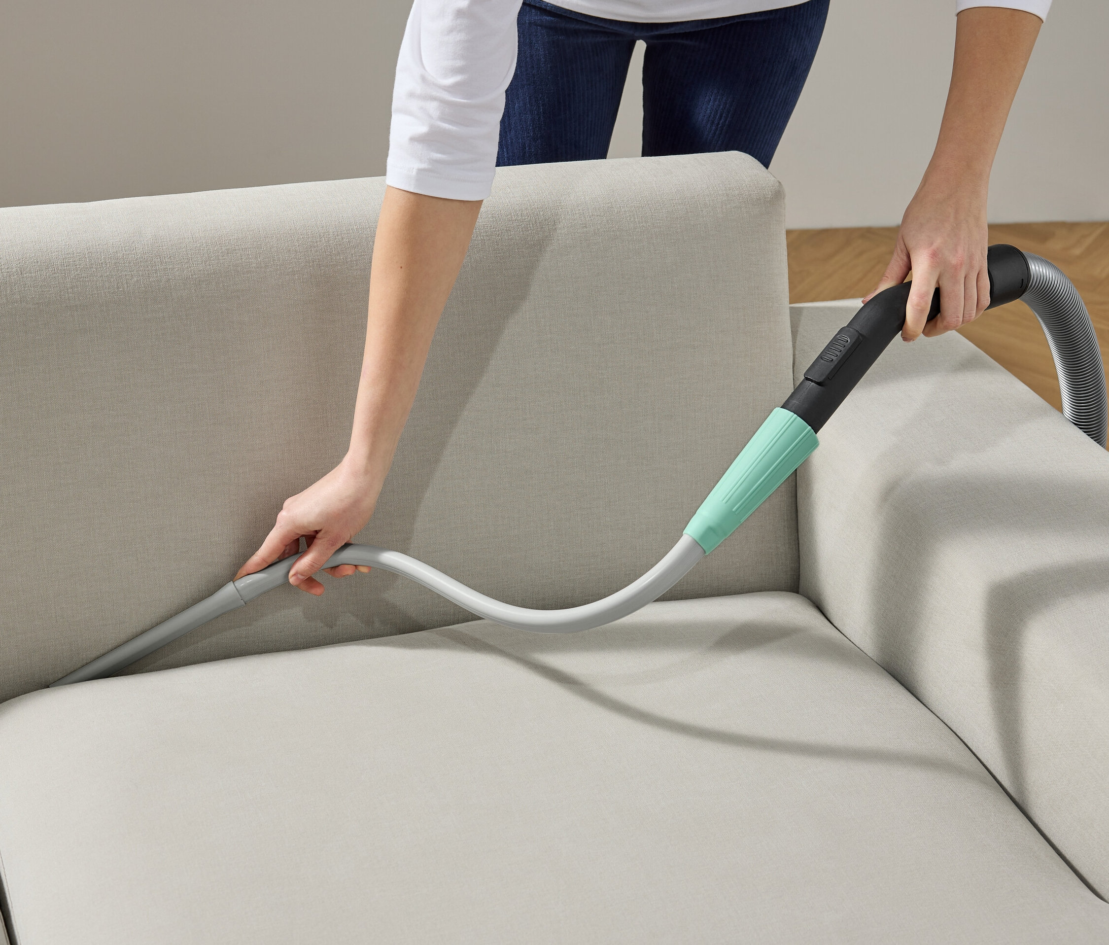 Žena používá nástavec na vysavač k čištění pohovky.