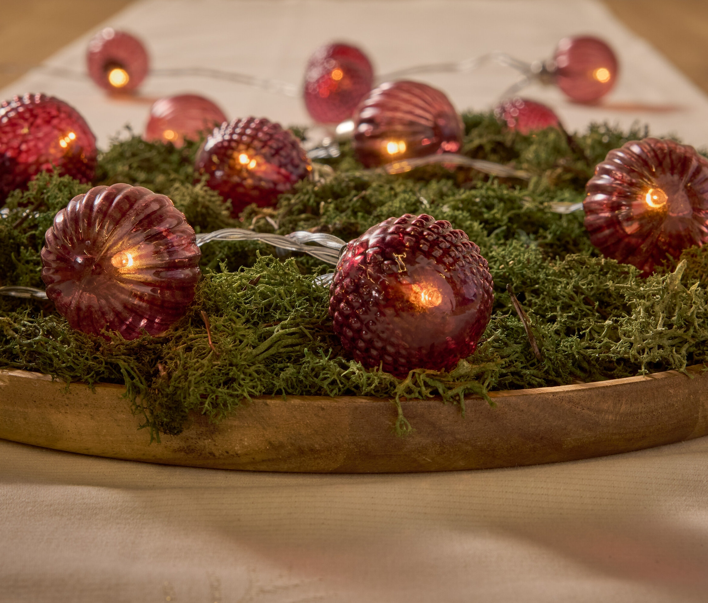 Dekorativní červená světla na mechu v dřevěné misce.