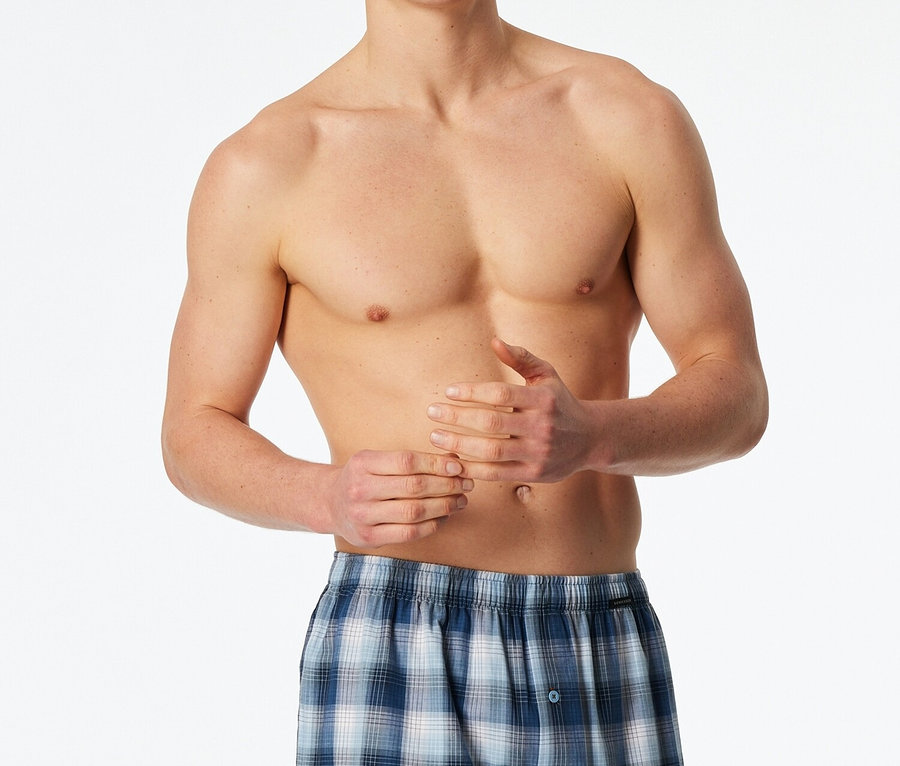 Muž bez košile má na sobě modré kostkované boxerky.