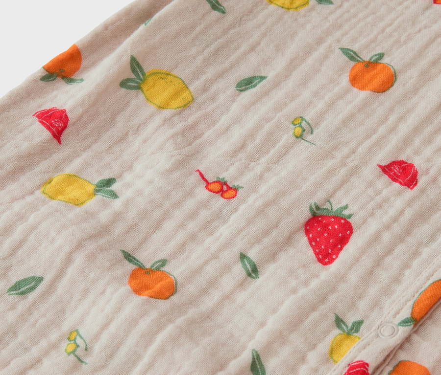 Detail látky s ovocným vzorem, včetně jahod, citronů a pomerančů.