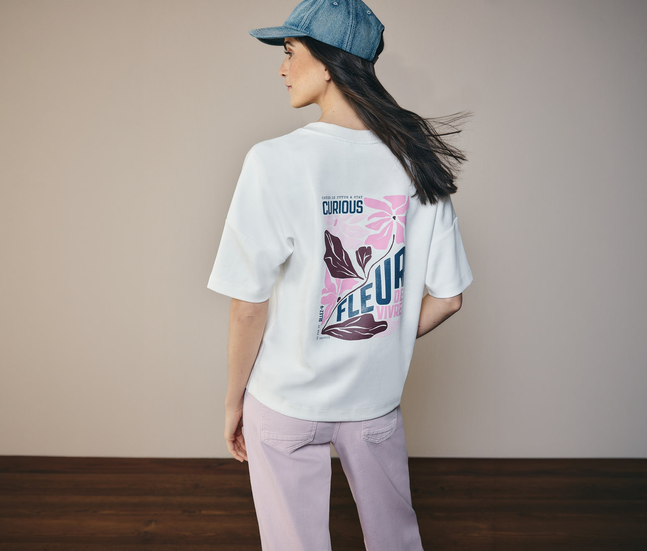 Žena zezadu v džínové bundě a mikině CECIL s květinovovým vzorem na zádech.