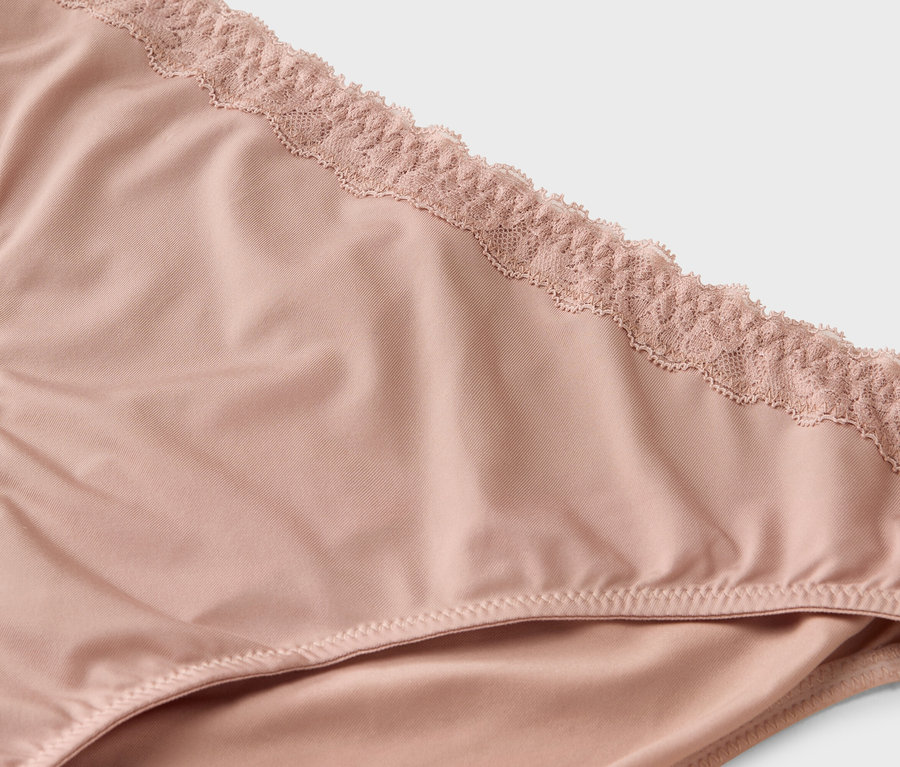 Detailní záběr na světle růžové kalhotky s krajkou.