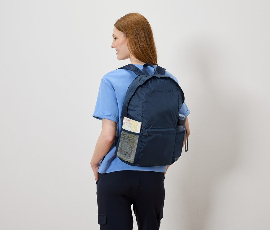 Žena zezadu s tmavě modrým batohem, ve kterém je mapa a láhev s vodou.