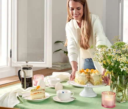 Žena podává dort vedle konvičky french press 800 ml, 6 šálků, šampaň.