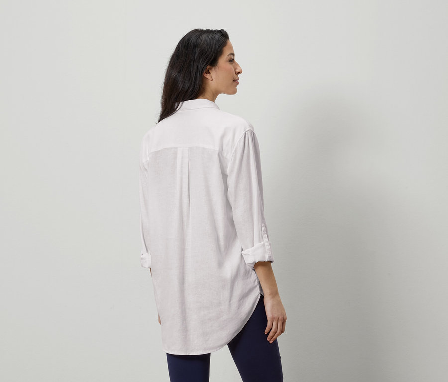 Žena zezadu v bílé košili a modrých legínách.