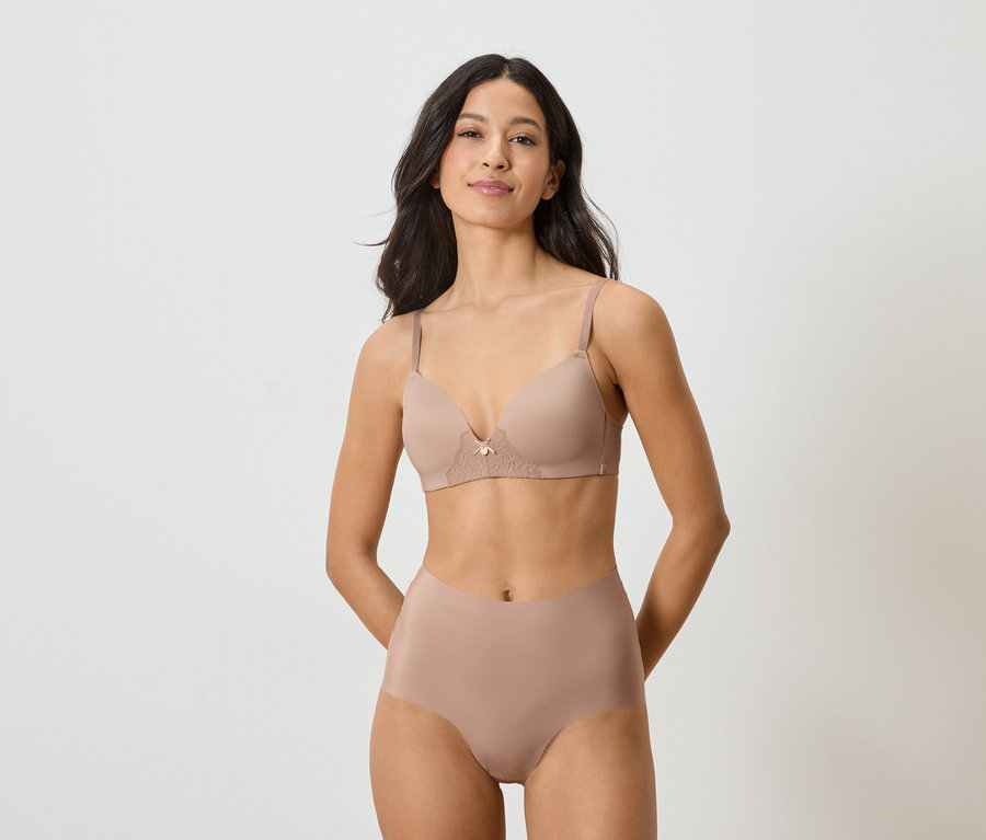 Žena má na sobě tělovou podprsenku a kalhotky na bílém pozadí.