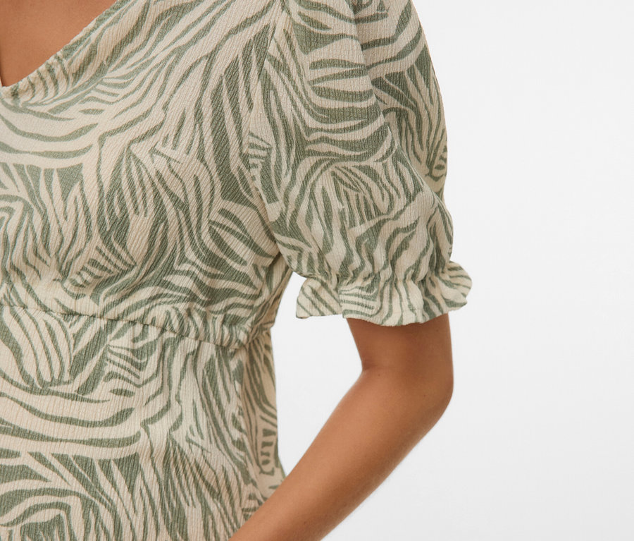 Detailní záběr ženy v šatech se zeleným zebřím vzorem.