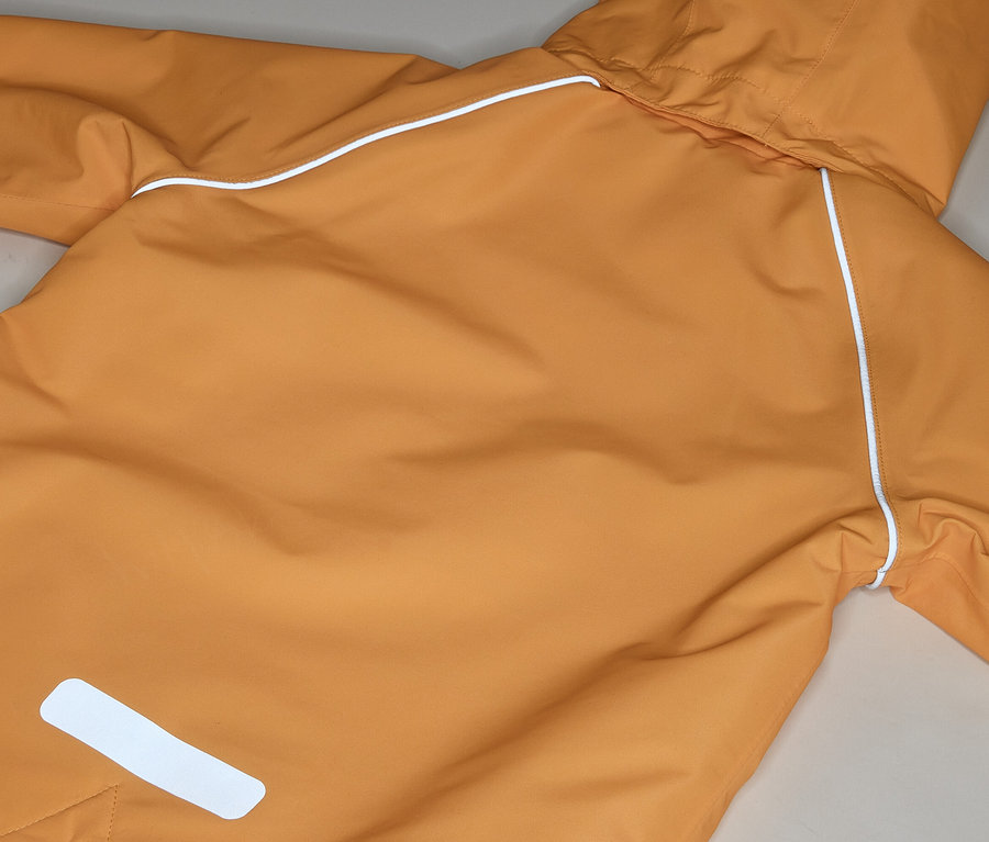 Detail oranžové bundy do deště s kapucí a bílými odrazkami.