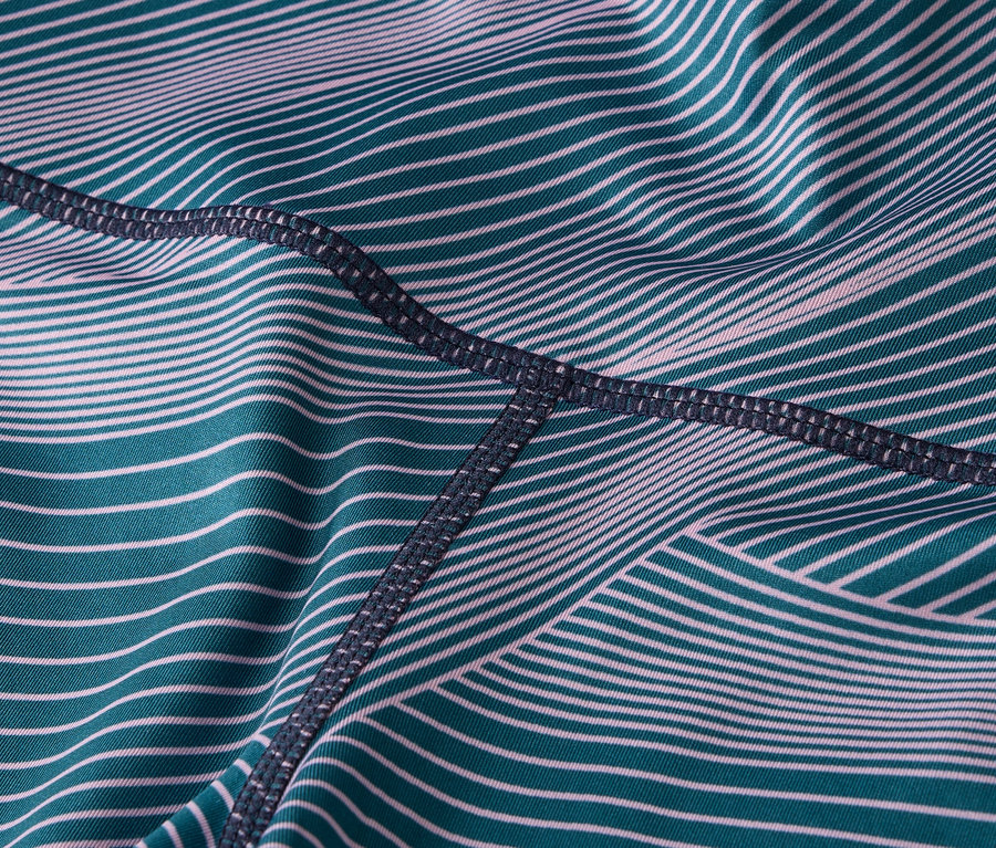 Detail látky legín s tyrkysovými a bílými pruhy a tmavým prošíváním.