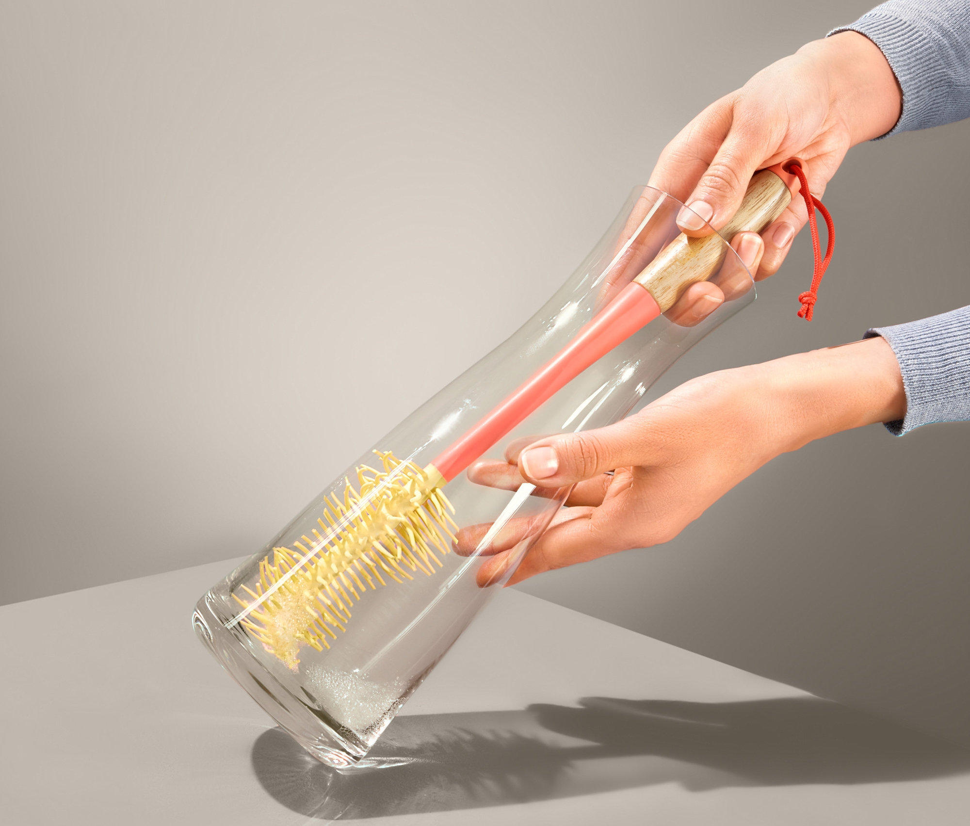 Žena čistí skleněnou vázu pomocí štětky na sklenice a lahve.