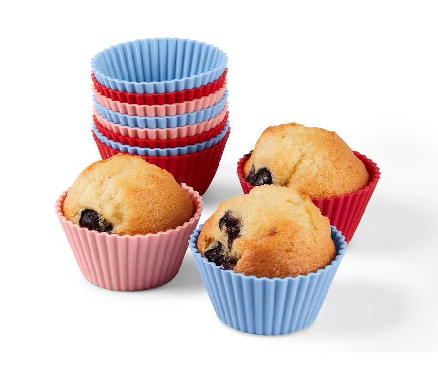 Tři muffiny v červených, růžových a modrých silikonových formičkách a stoh 12 formiček na muffiny.