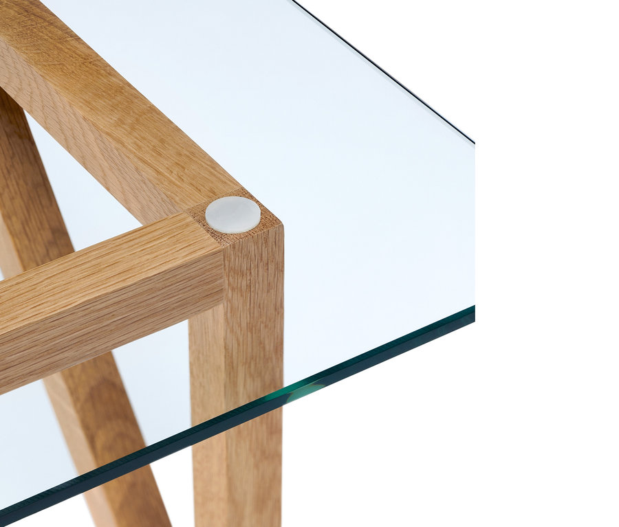 Detail rohu konferenčního stolku s dřevěnou konstrukcí a skleněnou deskou.
