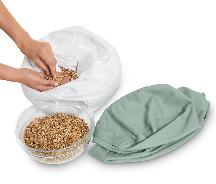 Žena plní meditační polštářek zrním z mísy a bílého pytle.