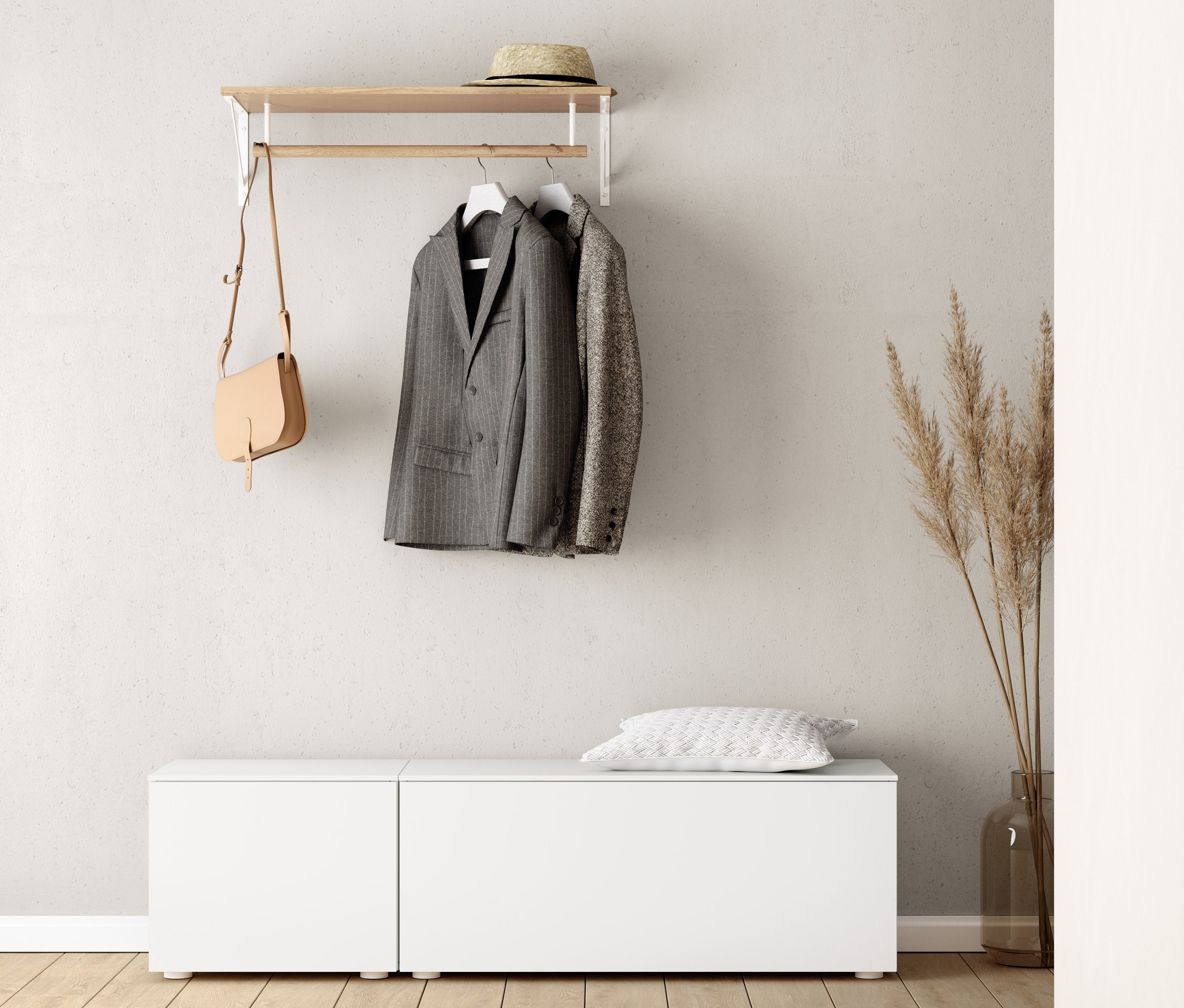 Na zdi je věšák na šaty, pod ním bílá lavice (cca 50 cm) a lavice (cca 100 cm). Na věšáku visí sako a kabelka. Na lavici leží polštář.