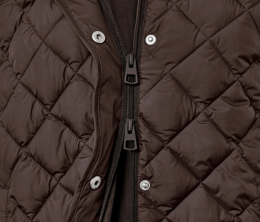 Detail hnědé dlouhé prošívané vesty s kapucí.